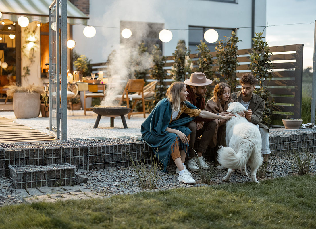 Personal Insurance - View of a Small Group of Friends Petting a Dog Having Fun Spending Time Together Sitting Outside on the Patio During the Evening